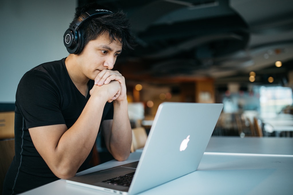 man with headphones on starting at macbook